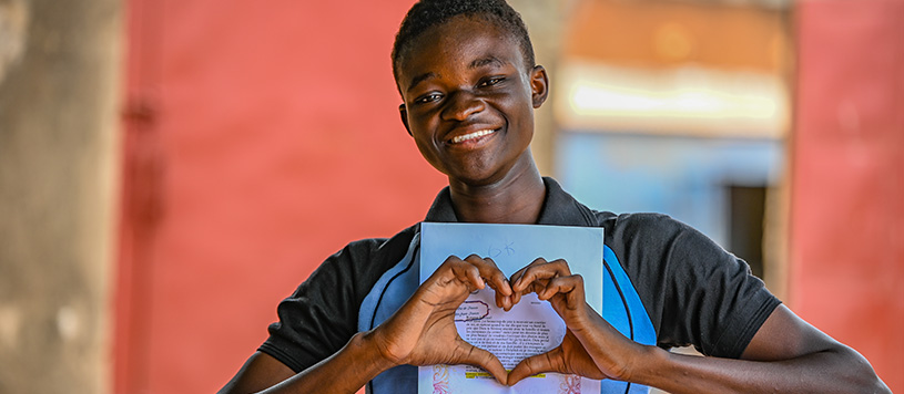 a boy makes a heart sign with his hands