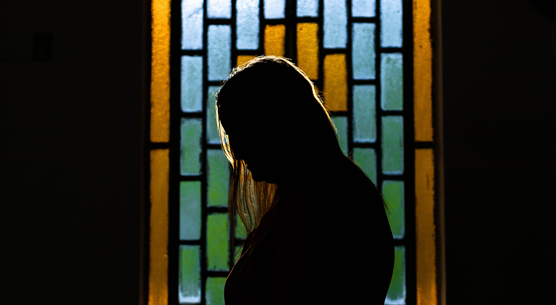 A silhouette of a child protection officer in front of a stained glass window.